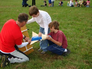 Ellis & Aryton II Teacher Doug Woolery helps two students prepare their rocket for launching.